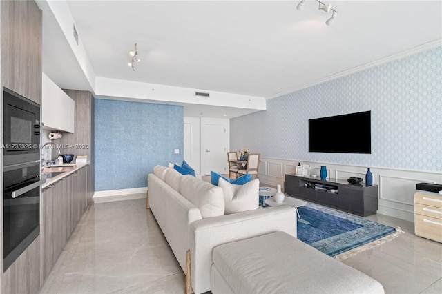 living room featuring sink, ornamental molding, and rail lighting