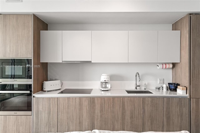 kitchen featuring extractor fan, sink, oven, white cabinets, and black electric stovetop