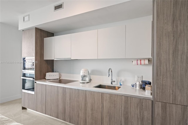 kitchen featuring sink, white cabinetry, black electric cooktop, built in microwave, and oven