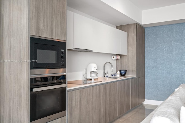 kitchen featuring sink, black electric stovetop, white cabinets, built in microwave, and stainless steel oven