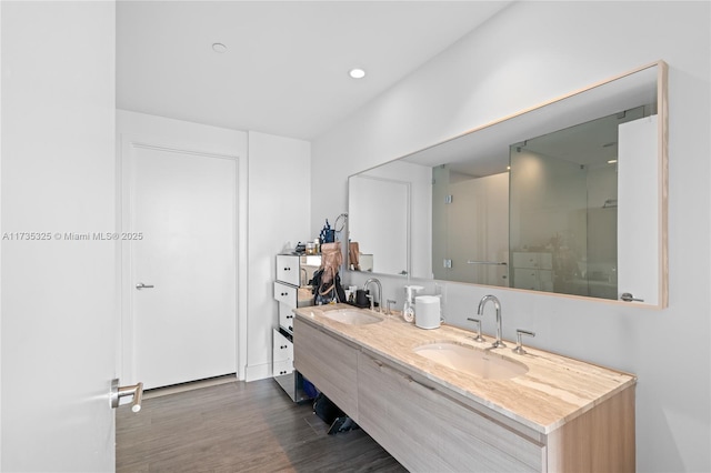 bathroom with wood-type flooring, vanity, and a shower with shower door