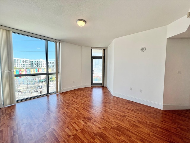 unfurnished room featuring hardwood / wood-style flooring, a textured ceiling, and a wall of windows