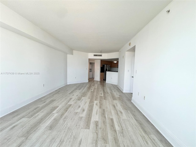 unfurnished living room featuring light hardwood / wood-style flooring and a textured ceiling