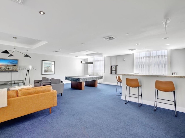 game room featuring a tray ceiling and dark carpet