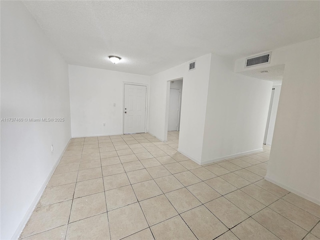 empty room featuring a textured ceiling and light tile patterned flooring