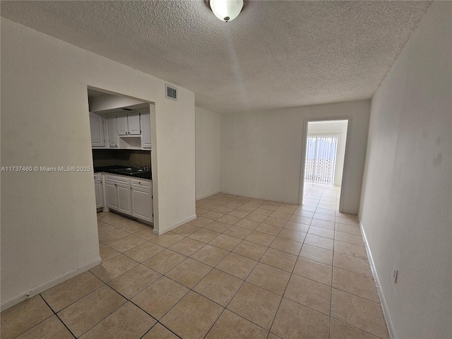 spare room featuring sink, a textured ceiling, and light tile patterned floors