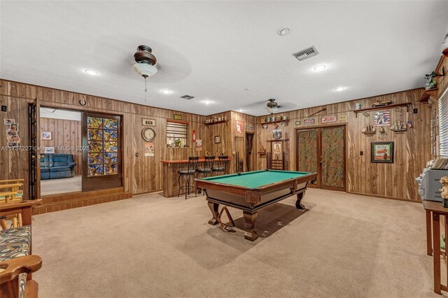 game room featuring wooden walls, carpet flooring, bar, and ceiling fan