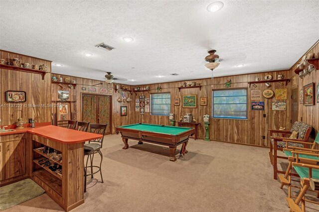 game room with wood walls, pool table, light colored carpet, a textured ceiling, and ceiling fan