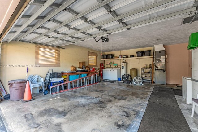 garage with heating unit, a garage door opener, electric water heater, and washer and dryer