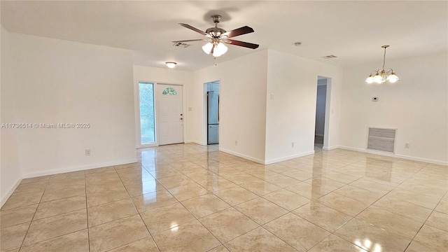 tiled spare room with ceiling fan with notable chandelier