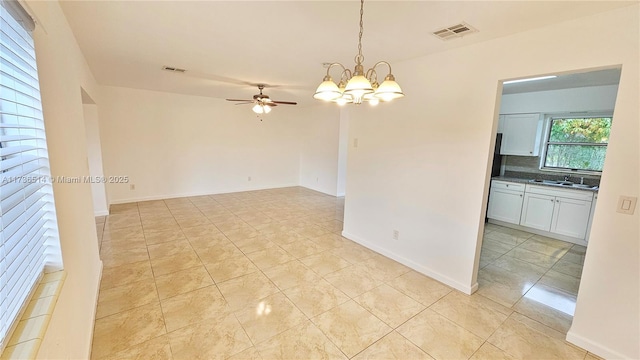 tiled empty room featuring sink and ceiling fan with notable chandelier