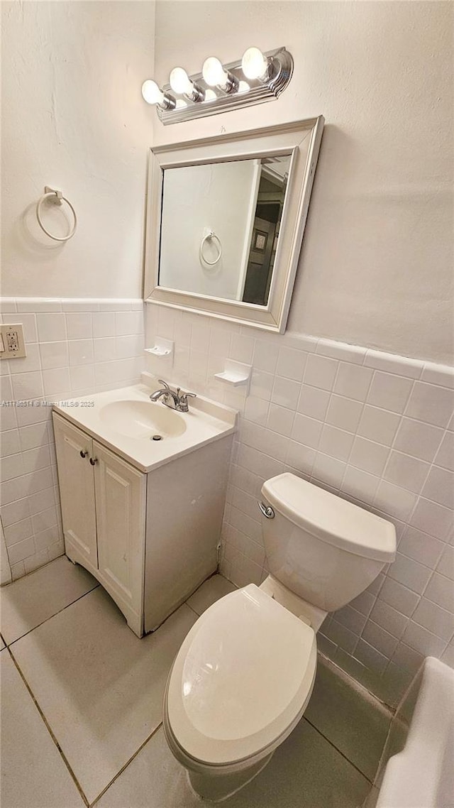 bathroom with vanity, tile walls, tile patterned floors, and toilet