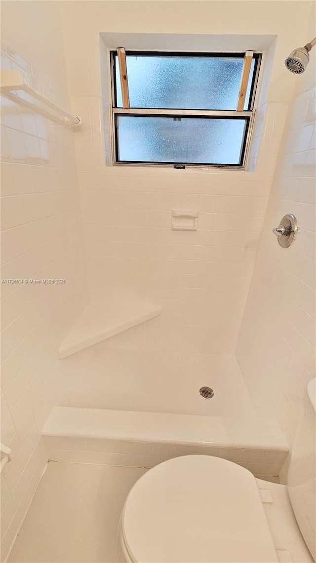 bathroom featuring toilet and a tile shower