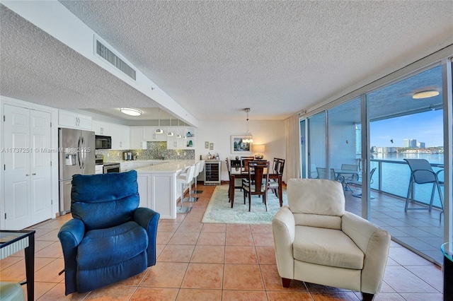 tiled living room with a textured ceiling and a wall of windows