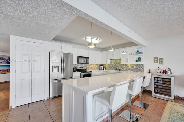 kitchen with a breakfast bar, wine cooler, white cabinets, kitchen peninsula, and stainless steel appliances