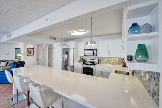 kitchen with appliances with stainless steel finishes, a breakfast bar, decorative light fixtures, white cabinetry, and kitchen peninsula