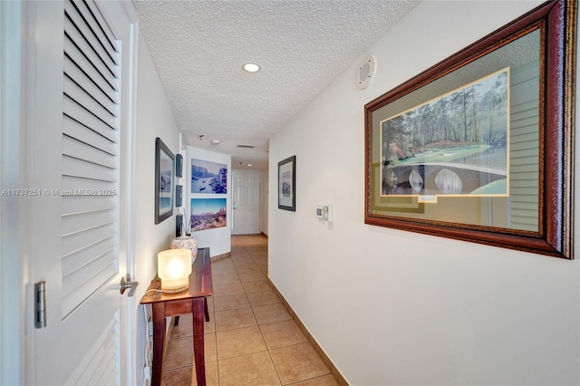 hallway featuring a textured ceiling and light tile patterned floors