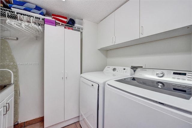 clothes washing area with cabinets, tile patterned flooring, washer and dryer, and a textured ceiling