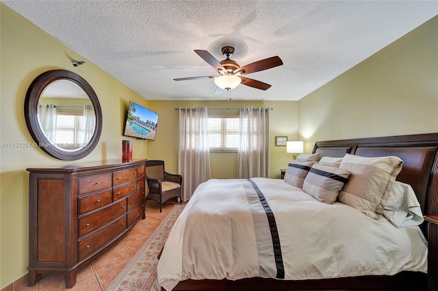 tiled bedroom with ceiling fan and a textured ceiling