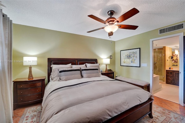 tiled bedroom with ceiling fan, connected bathroom, and a textured ceiling