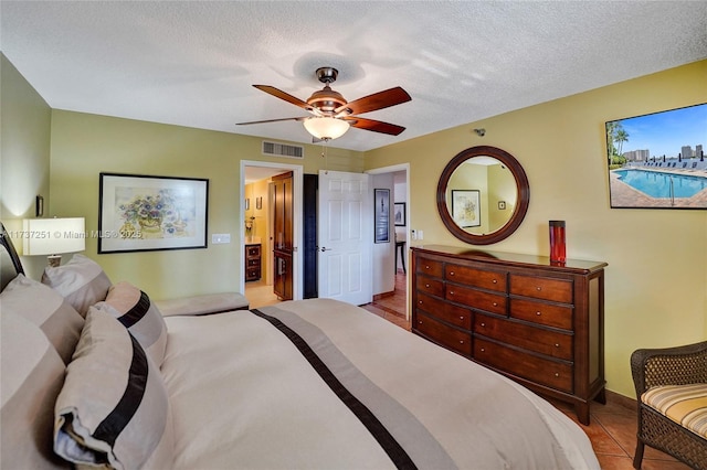 tiled bedroom with ceiling fan, ensuite bathroom, and a textured ceiling