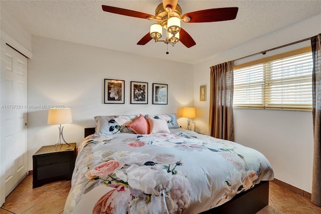 bedroom with light tile patterned flooring, a closet, ceiling fan, and a textured ceiling