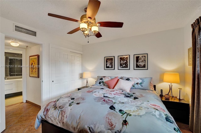 bedroom featuring connected bathroom, light tile patterned floors, a closet, and a textured ceiling