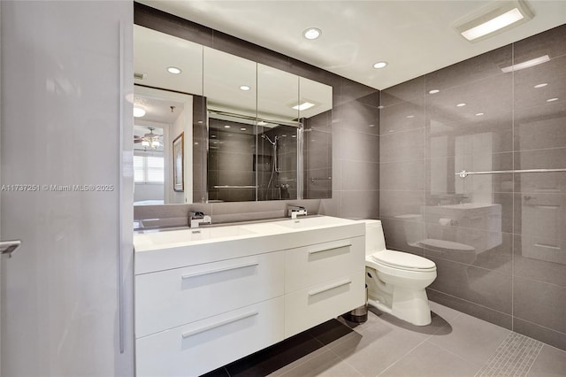 bathroom with walk in shower, toilet, tile walls, vanity, and tile patterned flooring