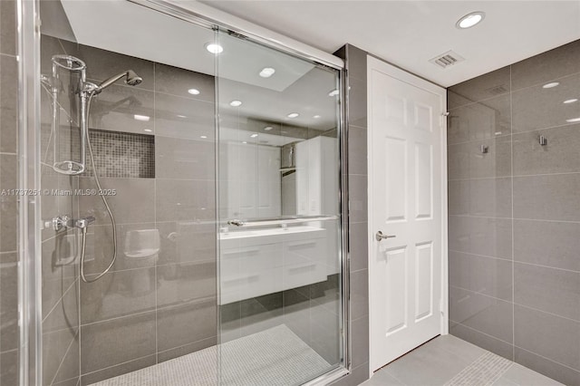 bathroom with tile patterned flooring, tile walls, and a shower with shower door