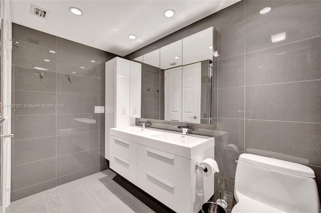 bathroom with vanity, toilet, tile patterned flooring, and tile walls