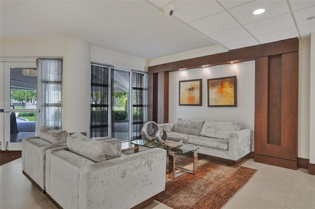 living room featuring a drop ceiling and tile patterned floors