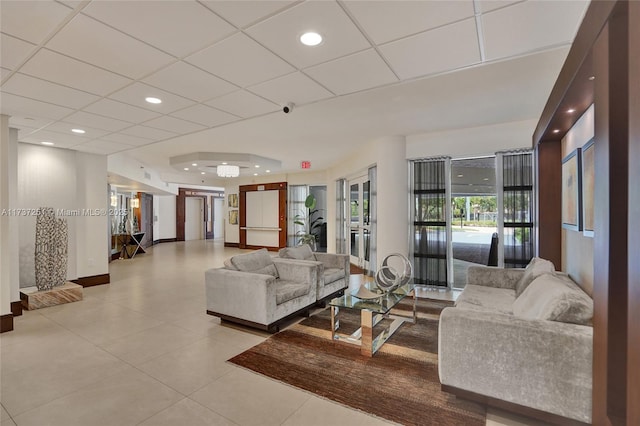 living room with light tile patterned flooring and a paneled ceiling