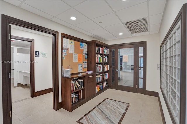 corridor featuring a drop ceiling, light tile patterned floors, and mail boxes