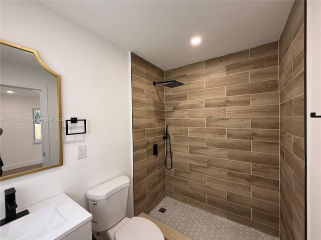 bathroom with vanity, toilet, and a tile shower