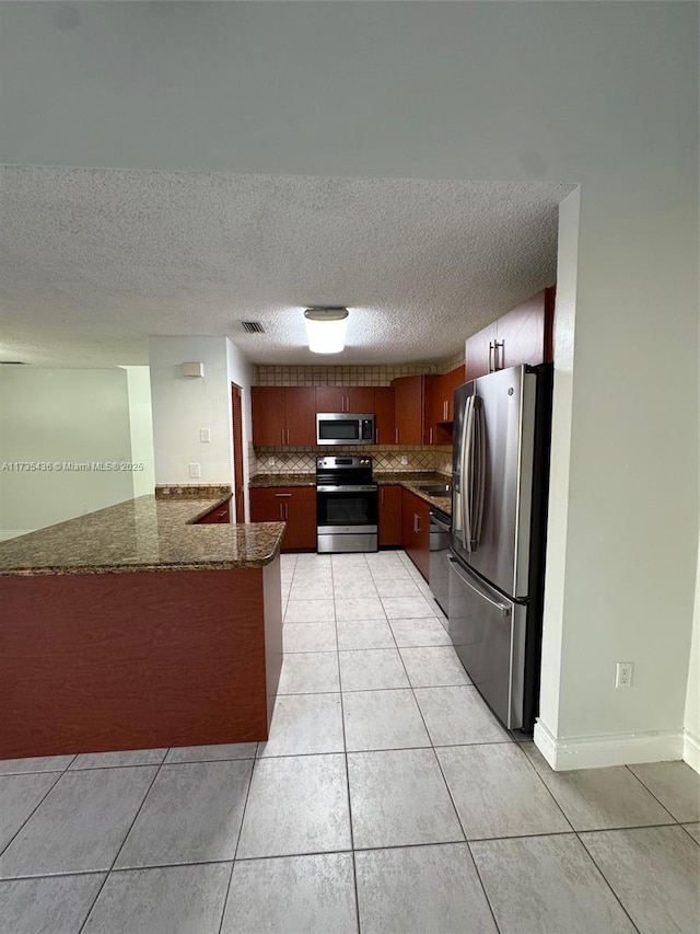 kitchen with stainless steel appliances, light tile patterned floors, decorative backsplash, and kitchen peninsula