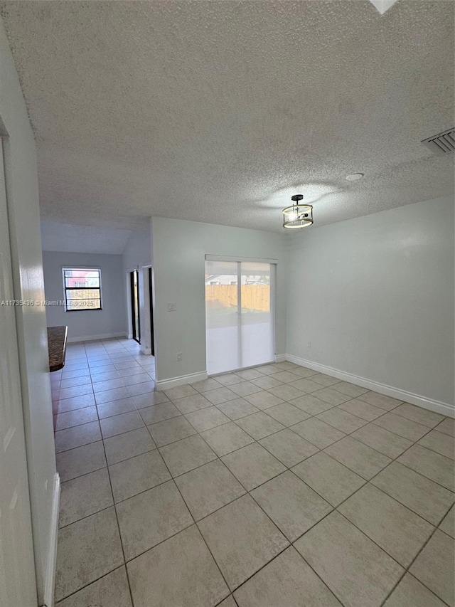 unfurnished room with light tile patterned flooring and a textured ceiling