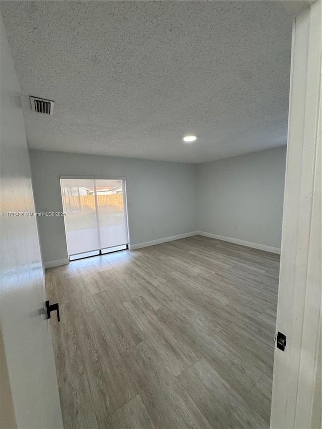 empty room featuring a textured ceiling and light wood-type flooring