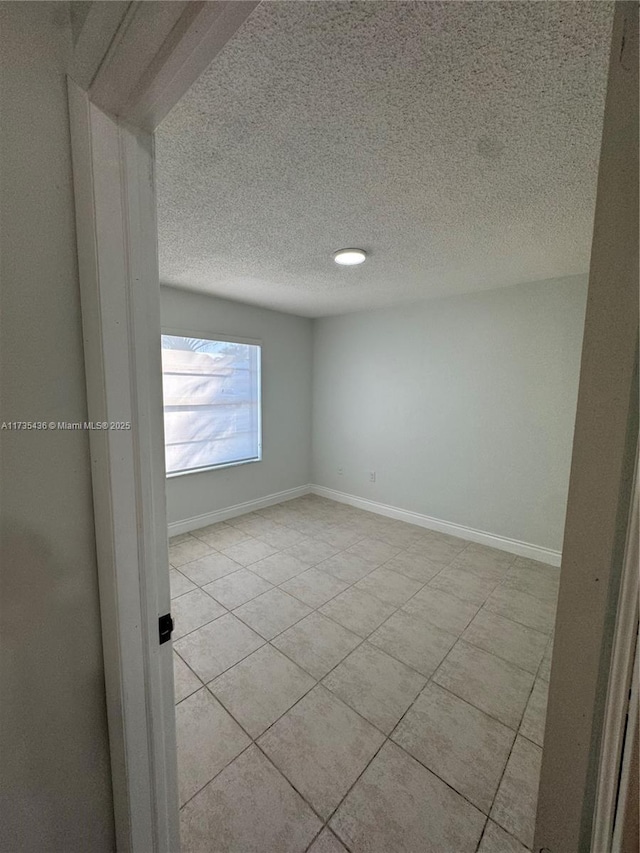 tiled empty room with a textured ceiling