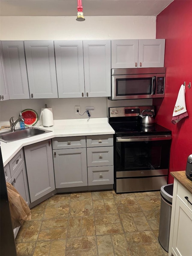 kitchen with sink, gray cabinets, and appliances with stainless steel finishes