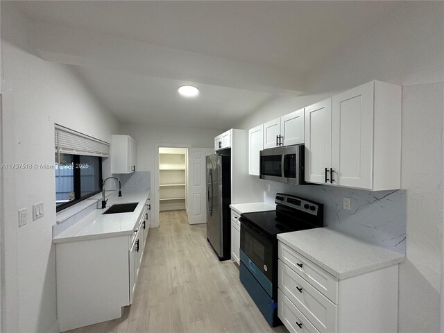 860 NW 171st St, Miami Gardens, FL 33169 - kitchen featuring sink, white cabinetry, light wood-type flooring, stainless steel appliances, and backsplash
