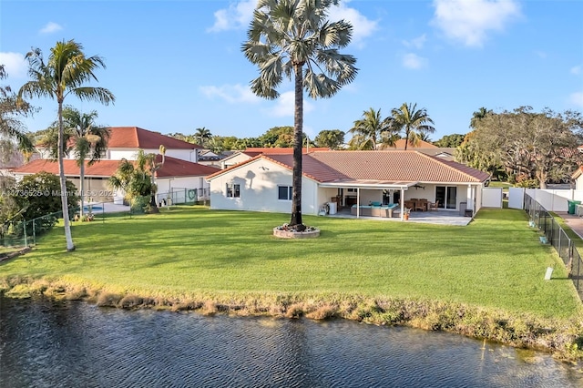 rear view of house featuring a water view, a yard, and a patio area