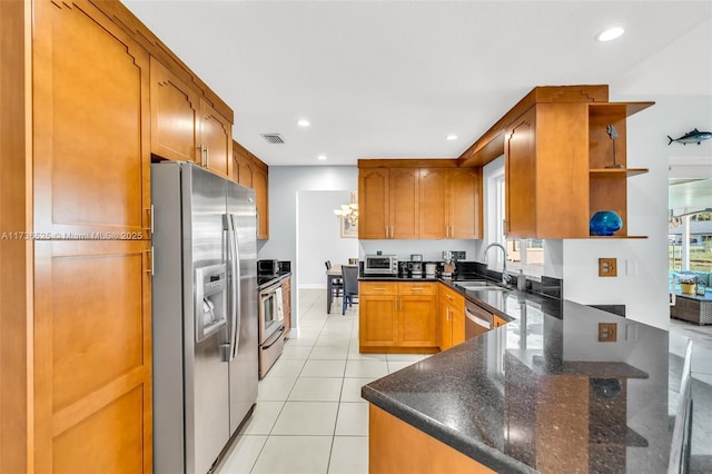 kitchen with sink, dark stone countertops, light tile patterned floors, appliances with stainless steel finishes, and kitchen peninsula