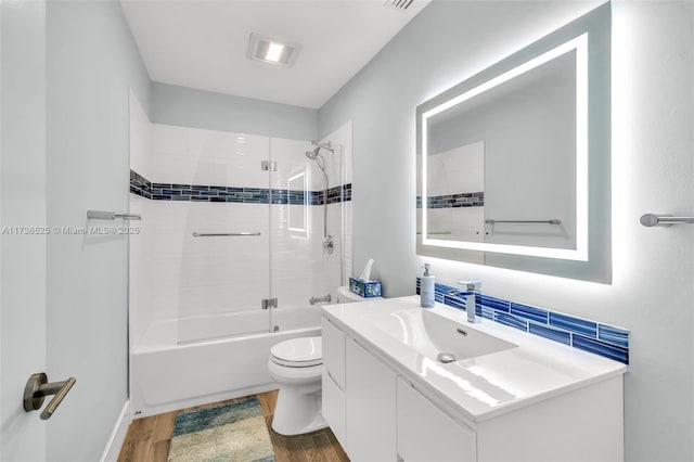 full bathroom with vanity, toilet, tiled shower / bath combo, and hardwood / wood-style floors