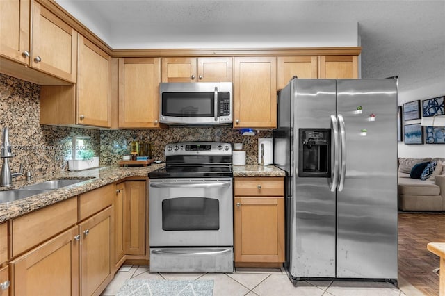 kitchen with sink, tasteful backsplash, light tile patterned floors, stainless steel appliances, and light stone countertops