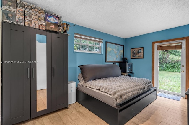 bedroom with light wood-type flooring, multiple windows, and access to outside