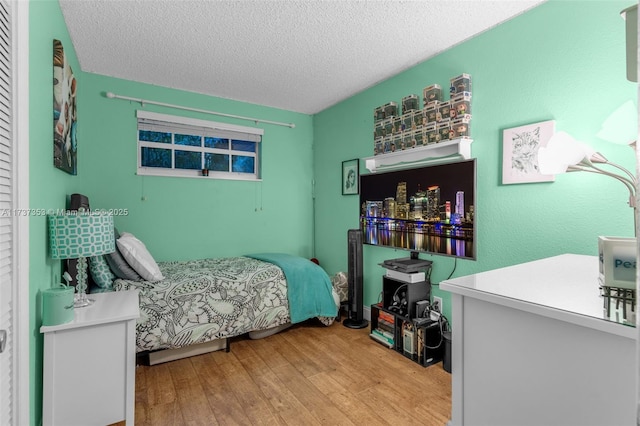 bedroom with a textured ceiling and light wood-type flooring