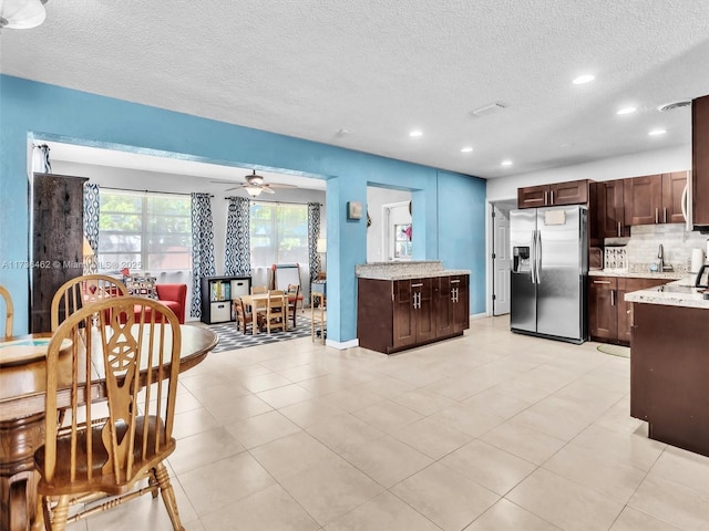 kitchen featuring tasteful backsplash, sink, ceiling fan, stainless steel refrigerator with ice dispenser, and a textured ceiling