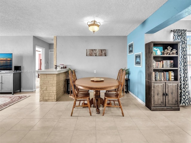 tiled dining space with a textured ceiling