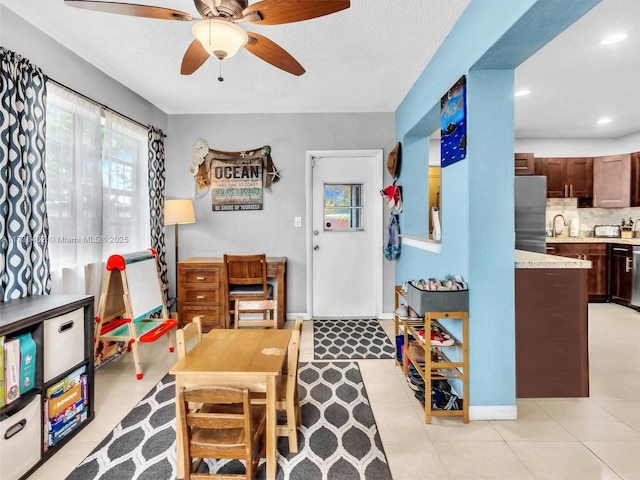 interior space featuring light tile patterned floors, a textured ceiling, sink, and ceiling fan