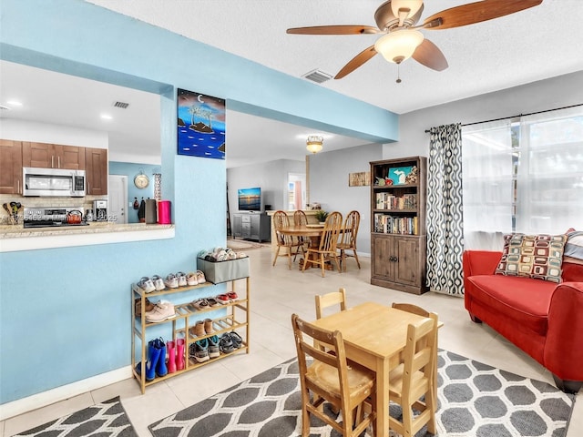 tiled dining room with ceiling fan and a textured ceiling